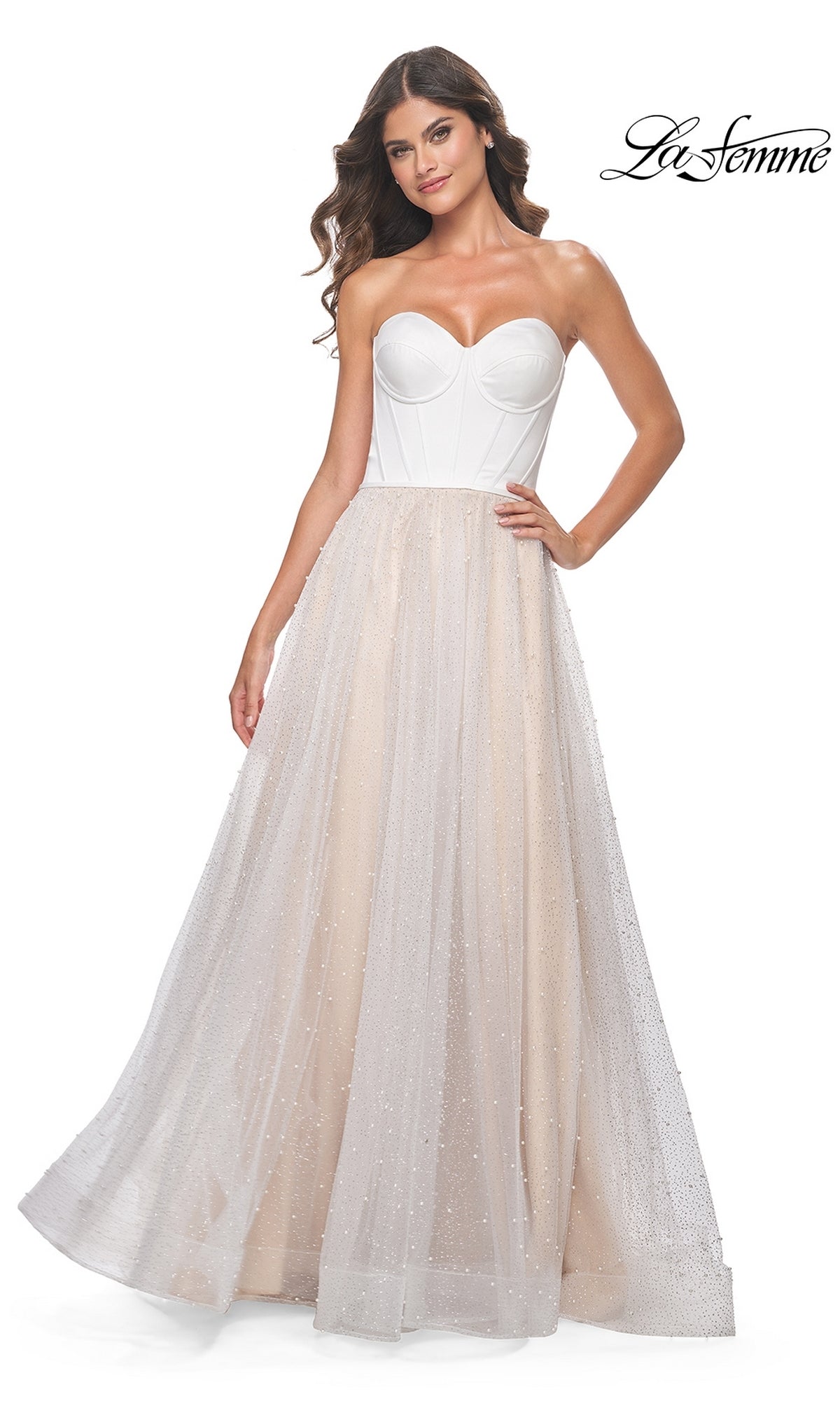 A woman poses with one hand on her hip, wearing the La Femme Strapless Long White Prom Dress 32149 featuring a sheer, sparkly tulle skirt. The